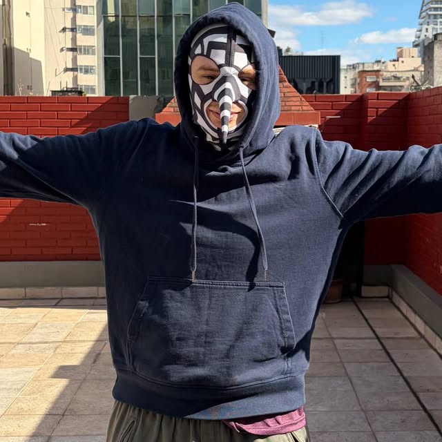Licenciado Dengue enmascarado, con los brazos abiertos en una terraza